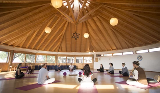 Group sitting in circle in the wooden roundhouse practice hall